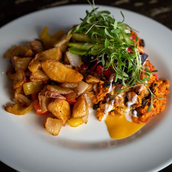 A plate of Wayward Cafe's comfort-food breakfast with home fries, scrambled eggs, avocado, and microgreens.