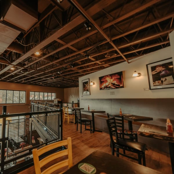 The Wayward Cafe's interior features wooden tables, chairs, and a balcony overlooking the lower level.