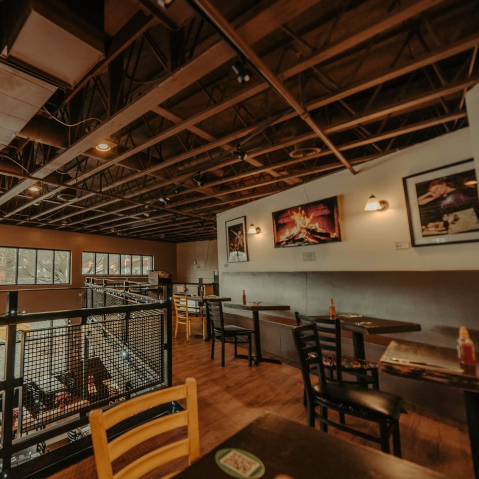 The Wayward Cafe's interior features wooden tables, chairs, and a balcony overlooking the lower level.